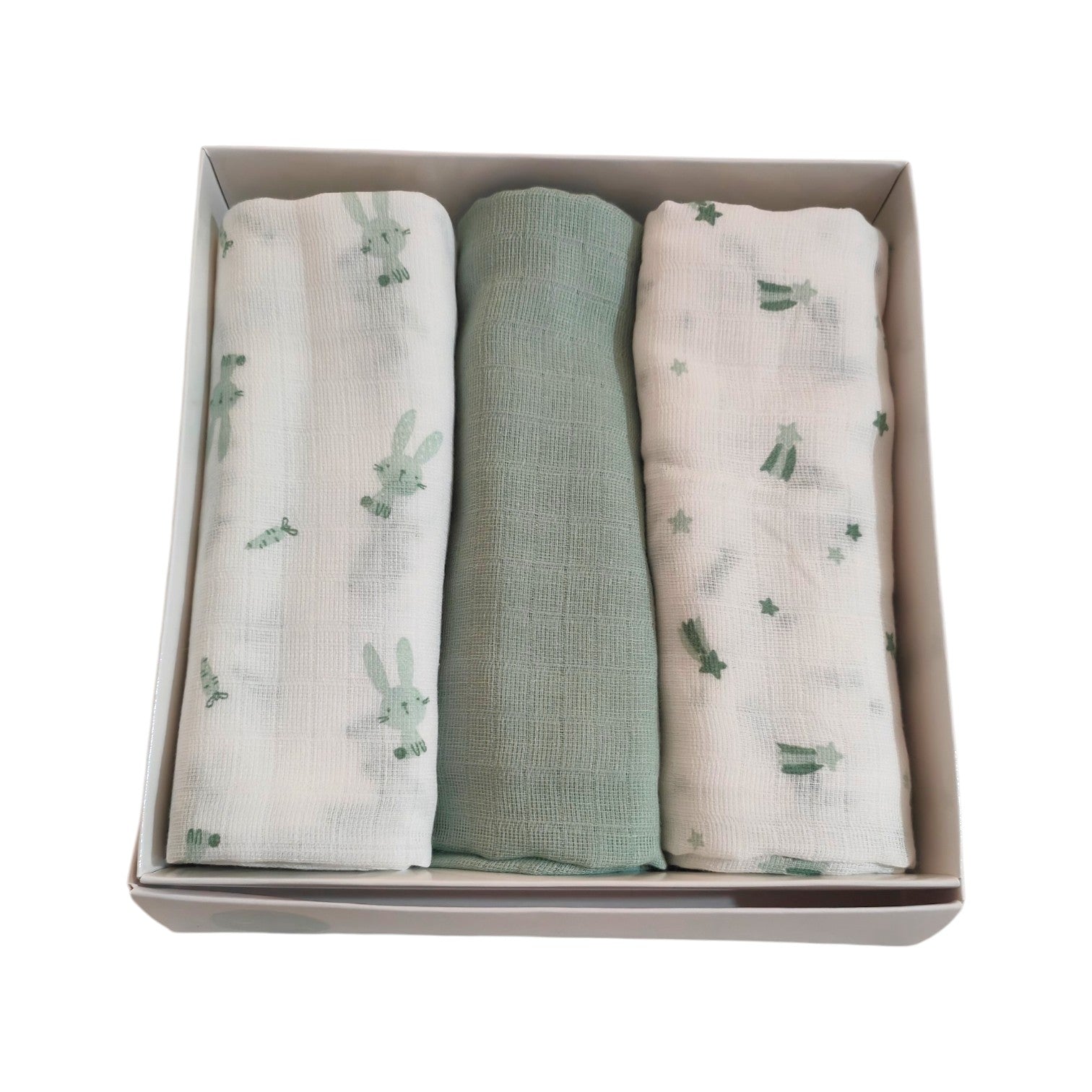 Set di 3 mussole per neonato in cotone arrotolate. Da sinistra: fantasia con stelline cadenti verde salvia, mussola a tinta unita verde salvia con trama double gauze visibile, e fantasia con coniglietti e carotine su sfondo bianco